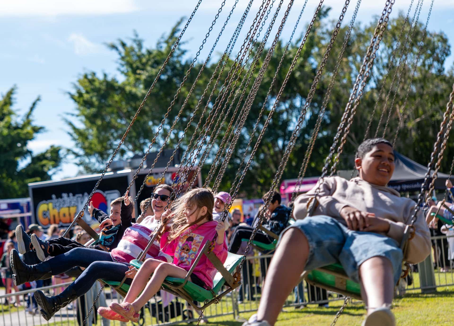Families enjoying swing ride at Crestmead Annual Outdoor Spectacular event in Queensland