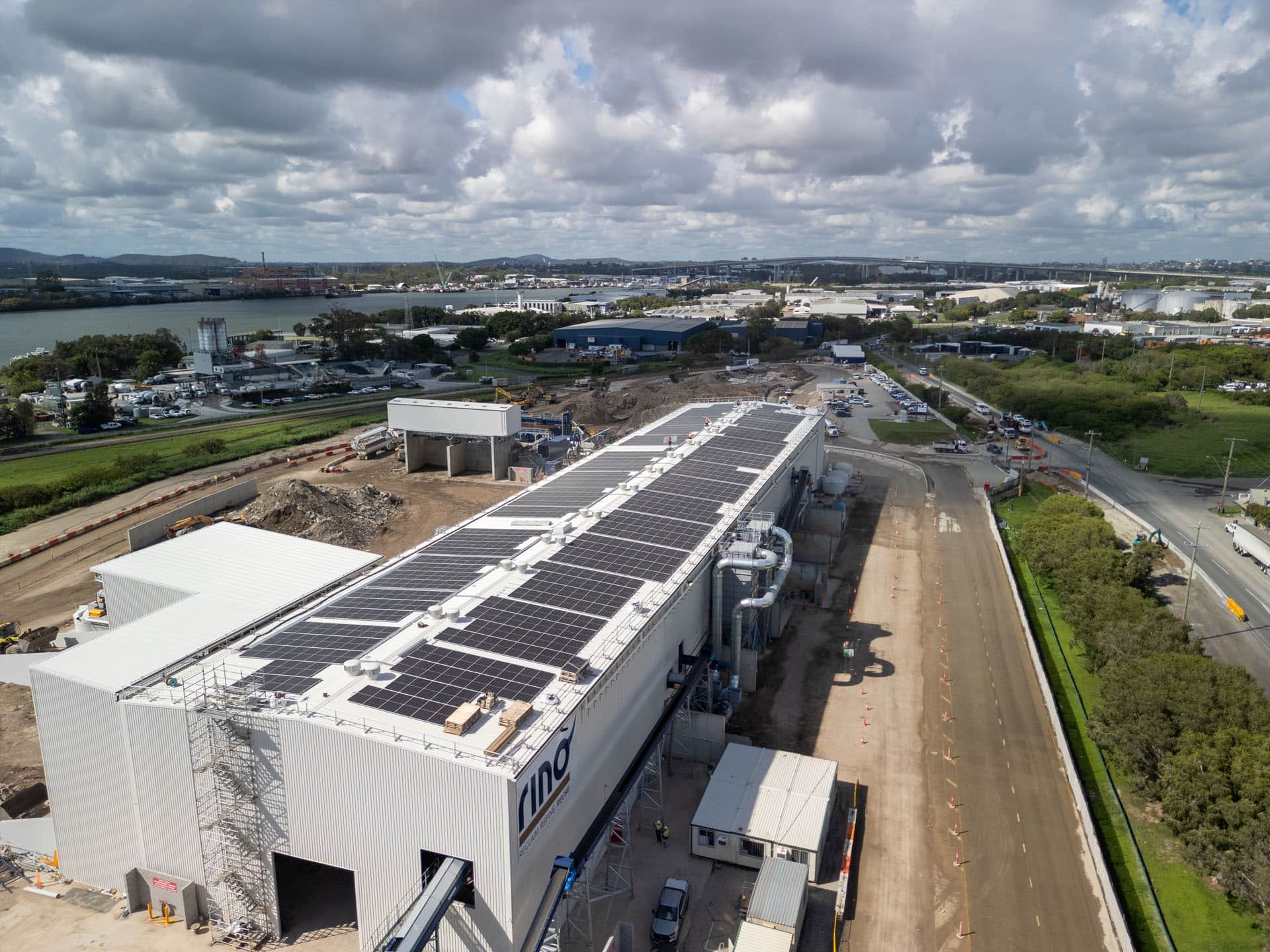 Aerial drone view of the Rino Recycling Facility under construction in Brisbane, showing solar panels installed on the industrial roof and surrounding site works.