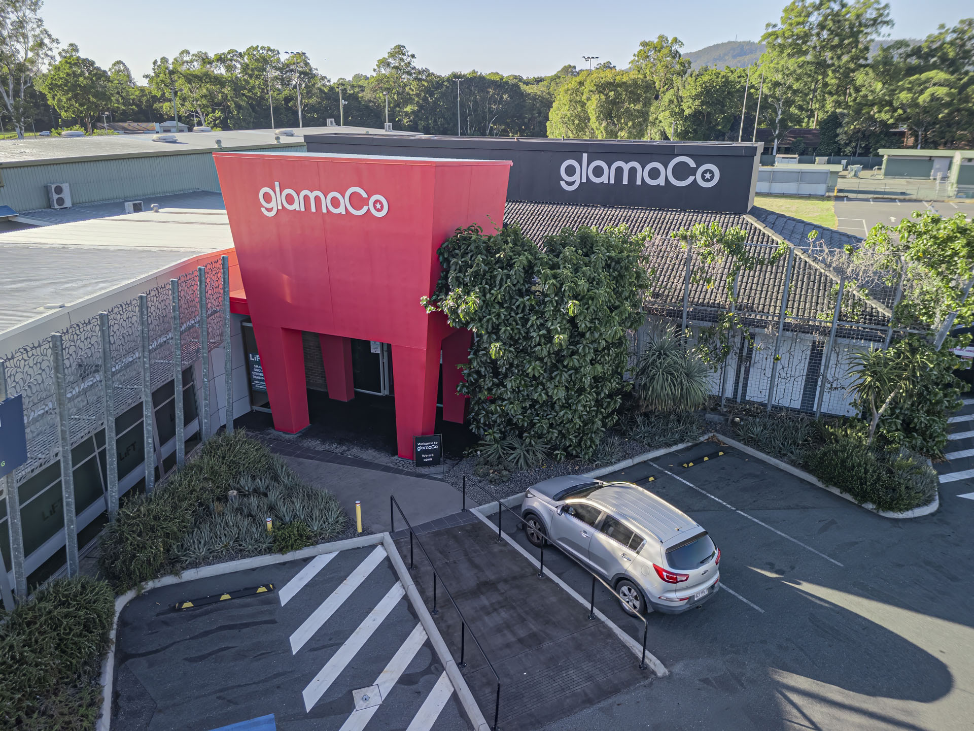 Angled exterior view of GlamaCo retail store with red branded façade in Queensland.