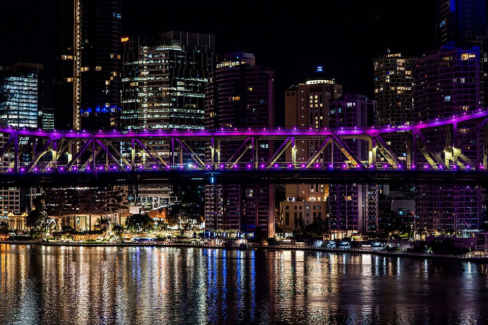 Aerial night view of Story Bridge in Brisbane with purple lighting and city skyline reflections during live infrastructure works.