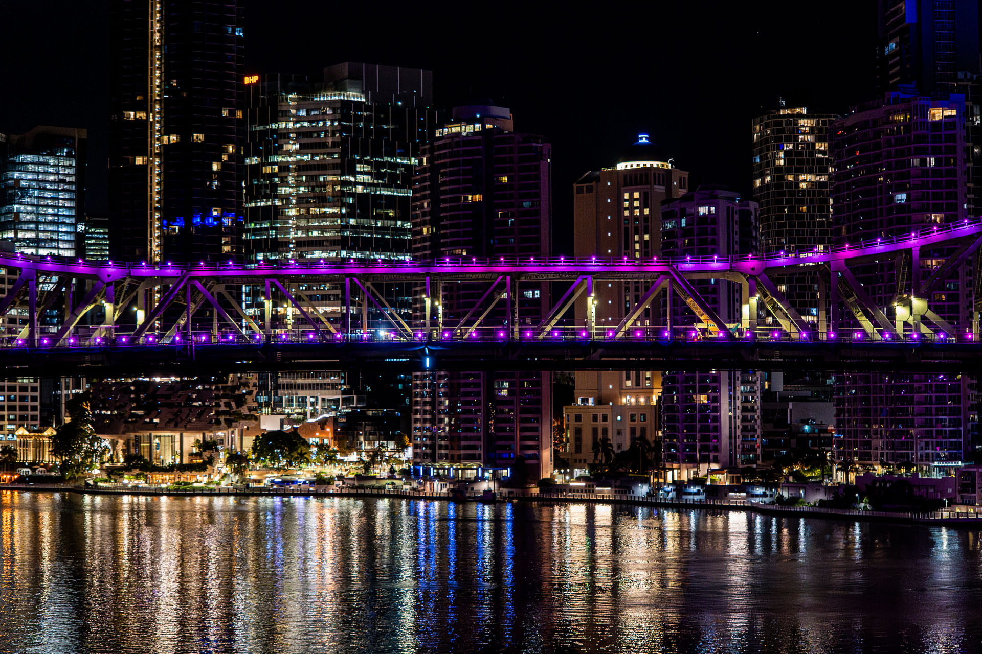 Aerial night view of Story Bridge in Brisbane with purple lighting and city skyline reflections during live infrastructure works.
