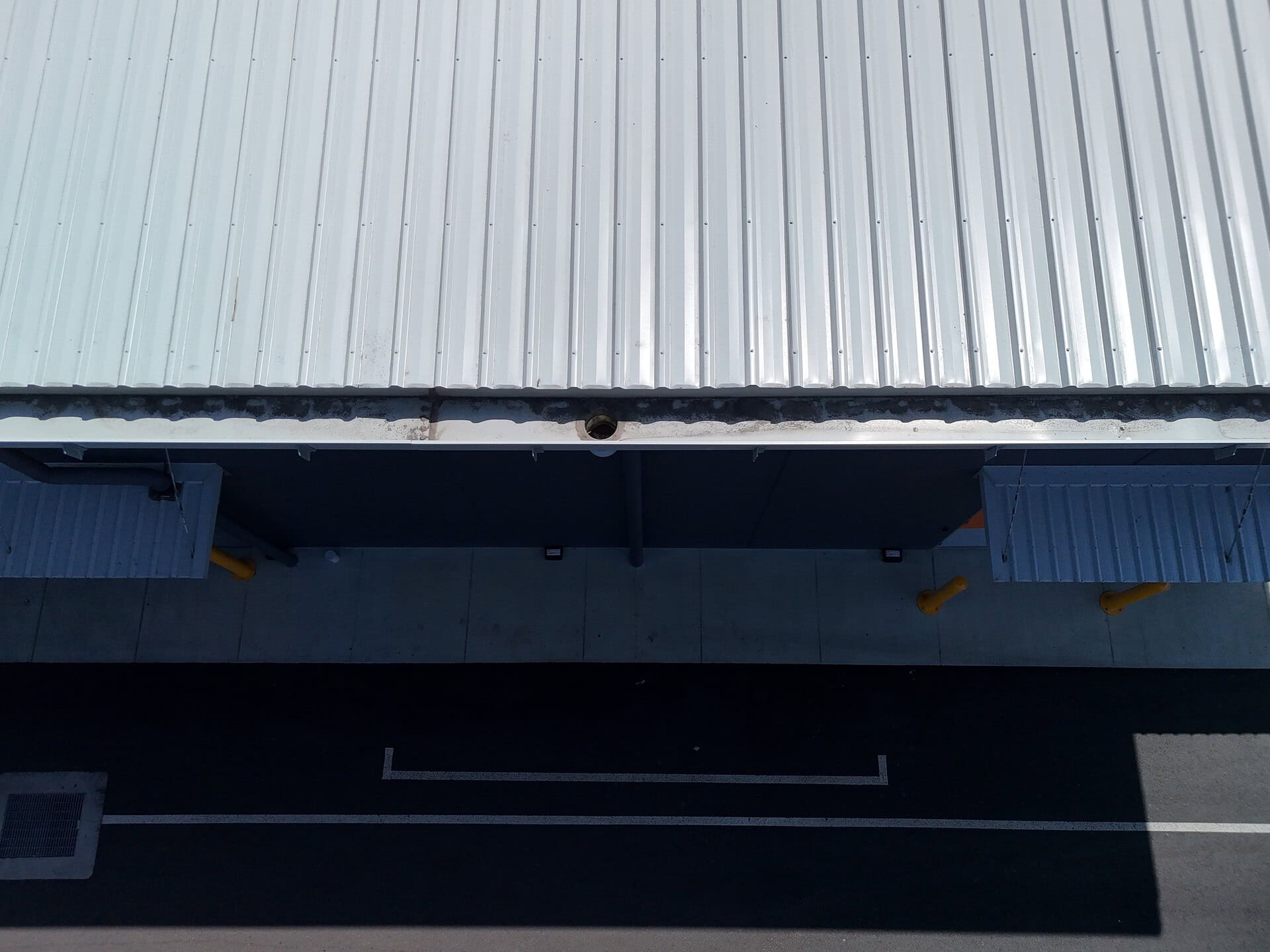 Overhead drone inspection of metal roof sheeting and gutter along a commercial building at Brisbane Markets